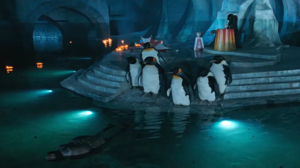 The Penguin lying dead as his penguin minions look on