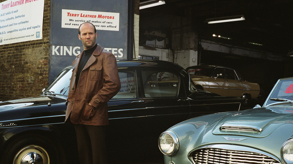 Jason Statham as Terry Leather stood with cars in The Bank Job (2008)