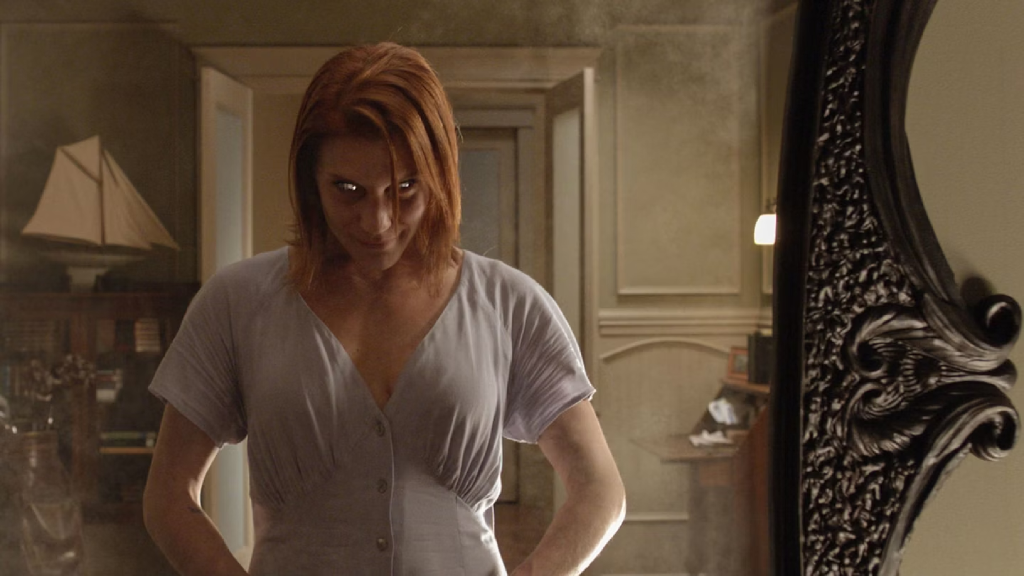 A woman staring intensely into a mirror in Oculus (2013)