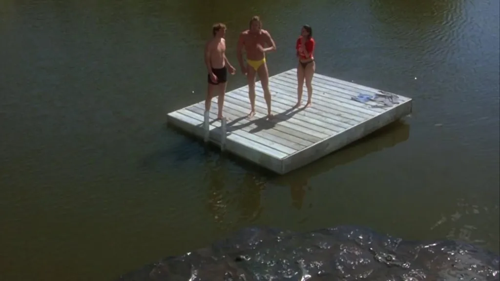 Three youths stand on a raft in the middle of a lake while a goop monster waits in Creepshow 2
