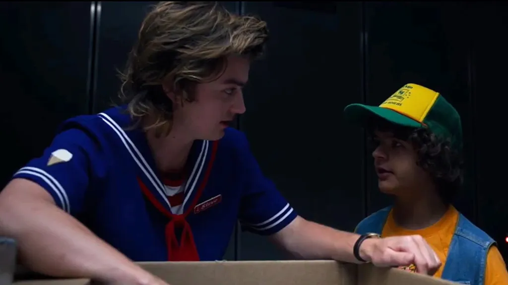 Steve and Dustin staring at each other while looking inside a box in Stranger Things Season 3