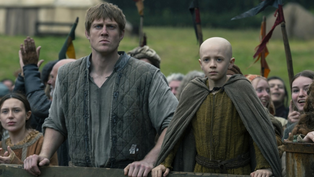 Ser Duncan the Tall and Egg leaning on a fence in front of a crowd in A Knight of the Seven Kingdoms