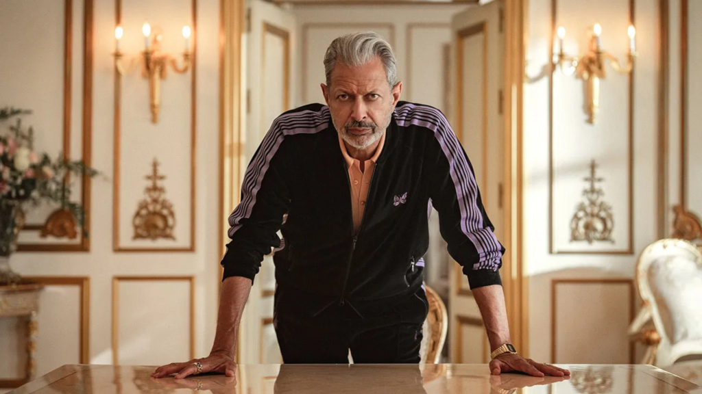 Jeff Goldblum leaning over a table in Kaos